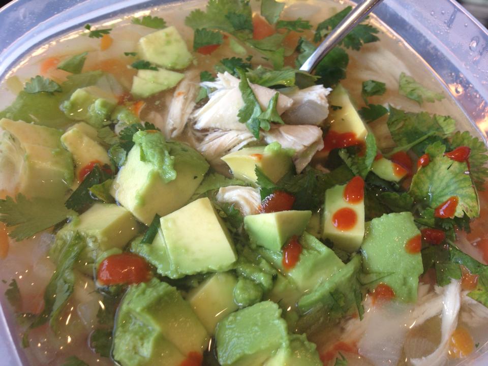 Homemade chicken soup with avocado, sriracha and cilantro